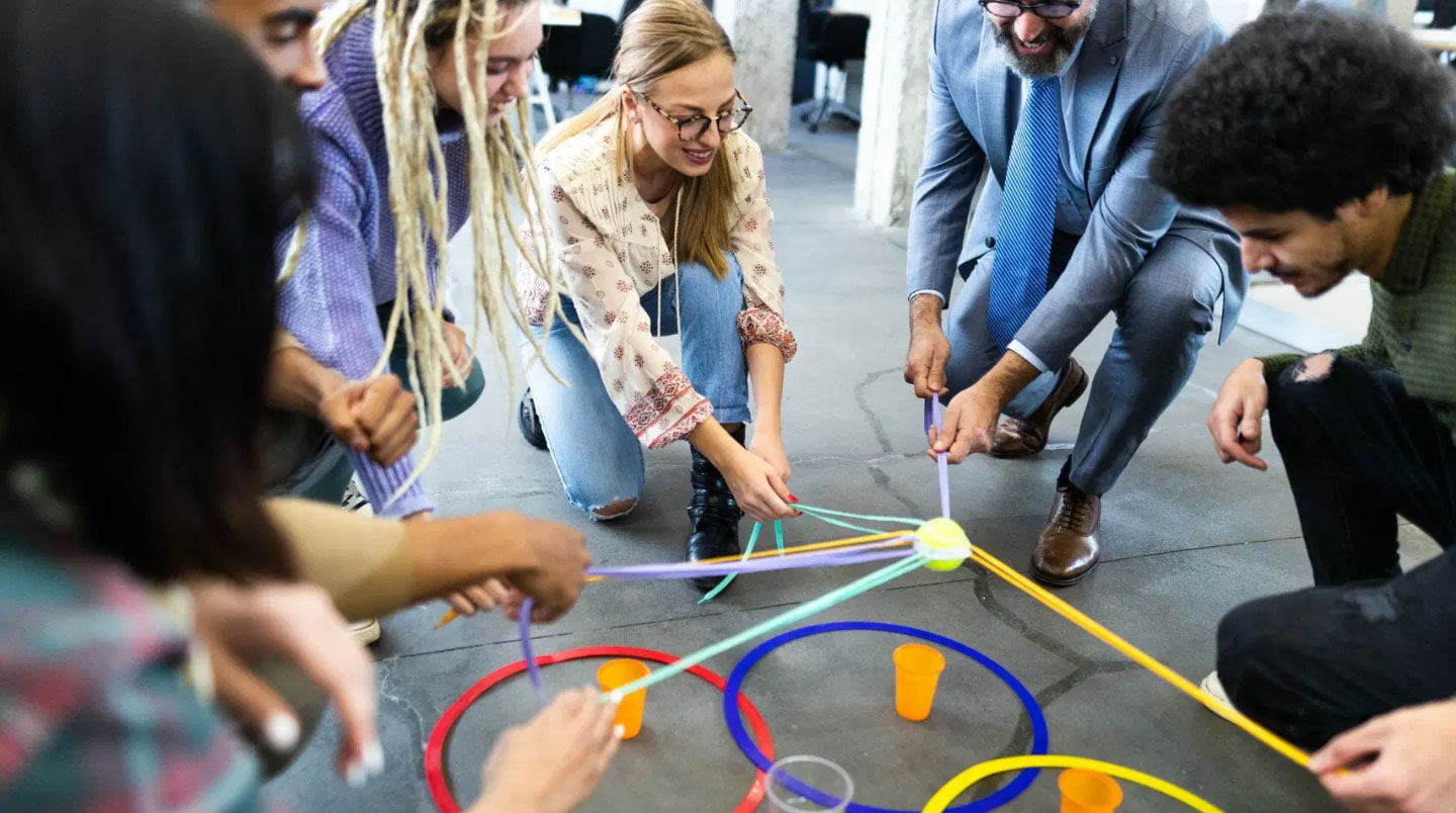 Gros plan sur les mains de participants manipulant des matériaux créatifs (peinture et argile) lors d'un atelier collaboratif, avec visage concentré d'une participante visible en arrière-plan flou